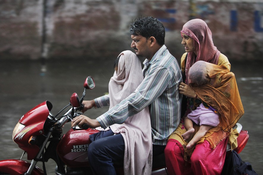 Família indiana enfrenta dificuldades para se locomover pelas ruas inundadas de Jammu, na Índia. Enchentes provocadas por chuvas de monção são frequentes no país nesta época do ano