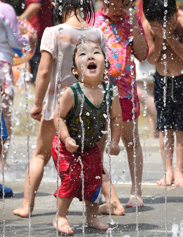 Criança toma banho em chafariz em um parque em Tóquio, neste sábado (26). Uma forte onda de calor invadiu o país no últimos dias (Foto: Toru Yamanaka/AFP)