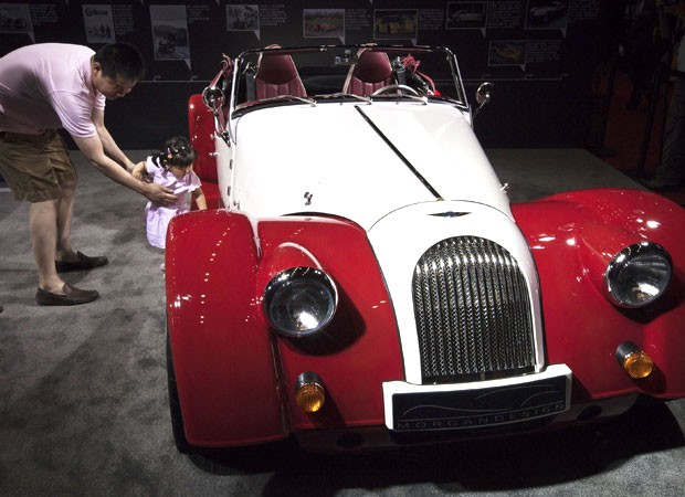 Um homem e sua filha posam ao lado do esportivo Plus 8, fabricado pela marca de luxo britânica Morgan. O veículo é exposto em uma exibição de itens de luxo em Pequim, na China, neste sábado (9). (Foto: Andy Wong/AP)