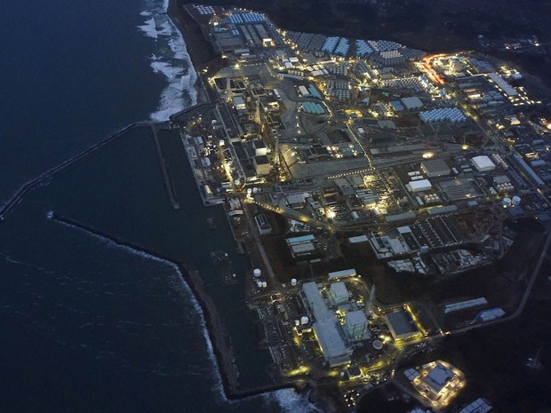 A usina de energia nuclear Fukushima Daiichi, atingida pelo tsunami de 2011, é vista iluminada no amanhecer em Okuma, no município de Fukushima, no Japão. O desastre ambiental completa 5 anos na sexta-feira (11) (Foto: Reuters/Kyodo)