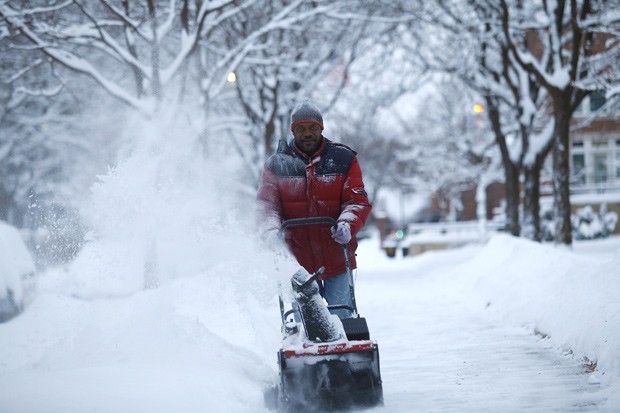   Foto tirada nesta segunda-feira (6) mostra homem retirando neve de uma calçada de Detroit, em Michigan, nos Estados Unidos. O estado foi atingido por uma grande tempestade de neve.  (Foto: Joshua Lott/Getty Images/AFP)