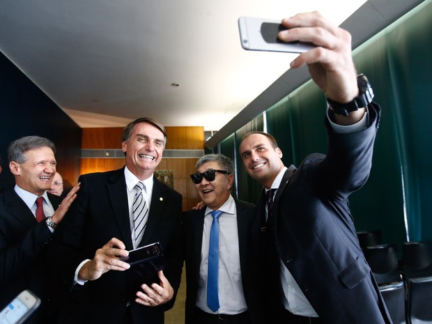 De férias e à paisana, o policial federal Newton Ishii posa para fotos com os deputados Eduardo Bolsonaro (PSC-SP) e Jair Bolsonaro (PP-RJ) durante visita ao plenário da Câmara dos Deputados, em Brasília (Foto: Dida Sampaio/Estadão Conteúdo)