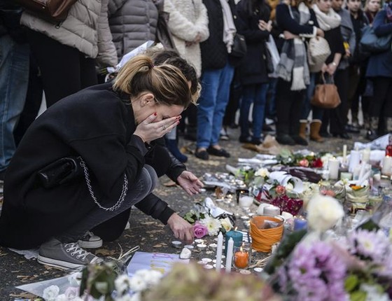 Pessoas colocam flores e acendem velas em tributo às vítimas de atentados de Paris, em frente ao salão de Bataclan, na França (Foto: EFE/CHRISTOPHE PETIT TESSON)