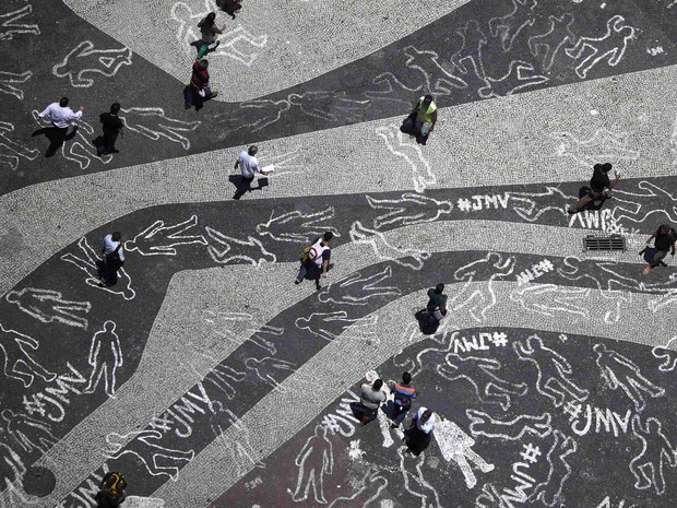  Movimento 'Juventude Marcada para Viver' pinta corpos pelo chão do Largo da Carioca em protesto contra a violência. Os desenhos representam as 4.000 vítimas de violência que morreram no estado do Rio de Janeiro. (Foto: Ricardo Moraes/Reuters)