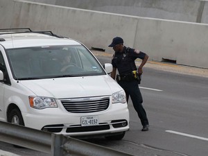 Policial checa documentos de motorista em frente ao portão do Forte Hood, no Texas, apó o alerta devido ao tiroteio na base militar (Foto: Deborah Cannon/Austin American-Statesman/AP)
