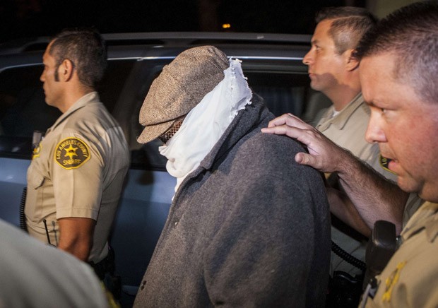Com  o resto encoberto, o produtor Nakula é escoltado por policiais em Los Angeles em 15 de setembro (Foto: Bret Hartman / Reuters)