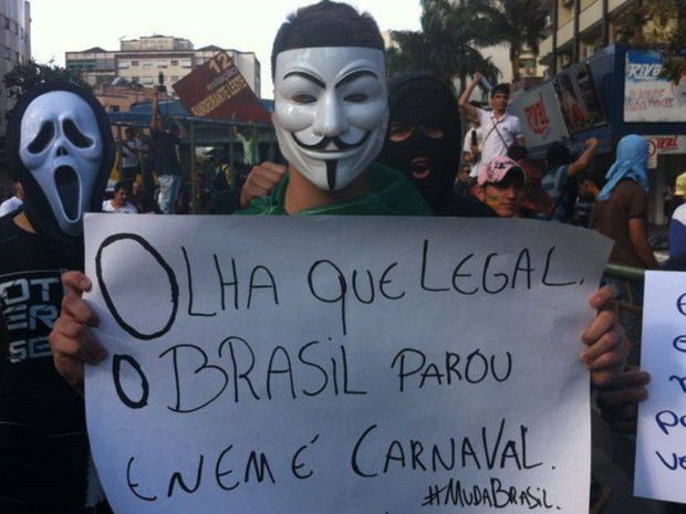 Jovem mascarado carrega cartaz com frase: 'Olha que legal, o Brasil parou e nem é Carnaval' (Foto: Cristina Cabral/ O Popular)