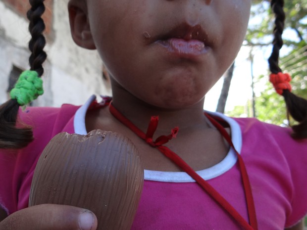 Menina que vive com a mãe pelas ruas de Maceió come chocolate doado por voluntários (Foto: Waldson Costa/G1)