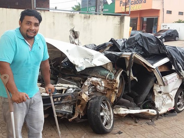 Ao lado de carro destruído, o jovem Tiago diz que não acredita ter sobrevivido após acidente grave (Foto: Felício Santiago/Arquivo Pessoal)