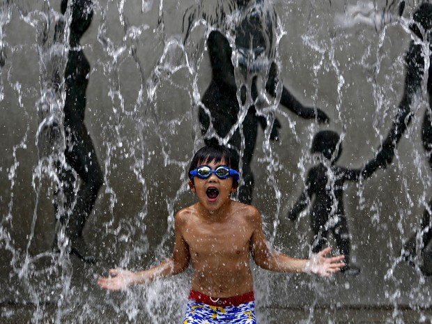 Um garoto brinca na fonte de um parque em Tóquio, no Japão. A temperatura na cidade chegou a 34ºC nesta segunda-feira (20) (Foto: Yuya Shino/Reuters)
