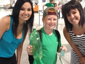 Charlaine e Claudia com Oisín no aeroporto; o garoto segura a garrafa que encontrou (Foto: André Quenneville -Tourisme Québec Mtl-Trudeau airport)