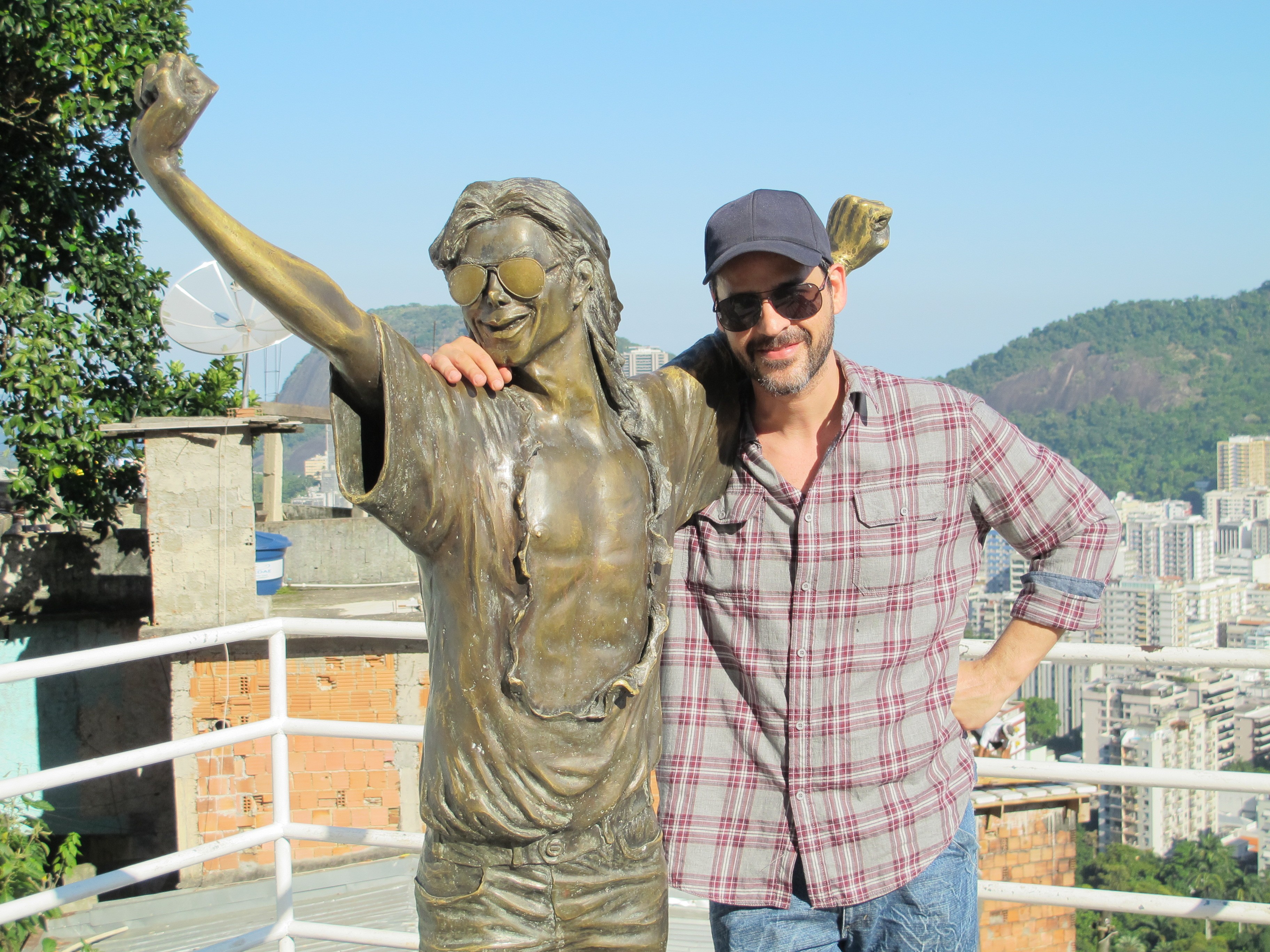 O ator posa com a  estátua em bronze do cantor Michael Jackson, que esteve na comunidade em 1996 (Foto: Divulgação)