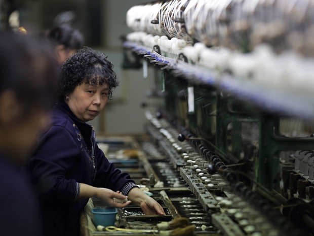 Mulher trabalha em fábrica de seda na província chinesa de Jiangsu. O Banco Central chinês disse no domingo (19) que cortará reservas bancárias para estimular financiamentos e evitar desaceleração da economia (Foto: Andy Wong/AP)