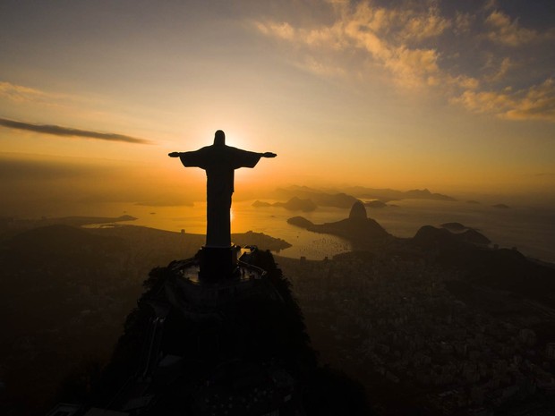 O amanhecer é visto por trás do Cristo Redentor diante da Baía de Guanabara, no Rio de Janeiro (Foto: Felipe Dana/AP)