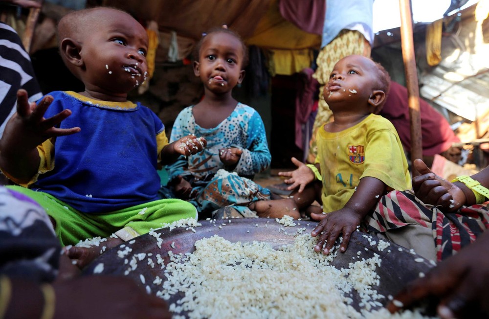 Crianças comem arroz cozido em abrigo provisório de sua família em  acampamento em Mogadíscio, na Somália (Foto: Feisal Omar/Reuters)