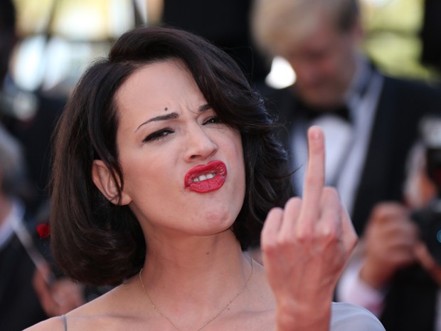 A atriz italiana Asia Argento faz gesto ofensivo para fotógrafos no tapete vermelho para o evento de exibição do filme 'Zulu'. O longa é o último a ser exibido no festival, que começou no dia 14 de maio e termina neste domingo (26), quando será conhecido (Foto: AFP PHOTO / LOIC VENANCE )