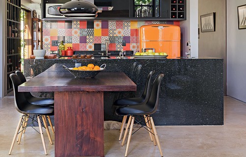 Na cozinha aberta para a sala de jantar o destaque é a geladeira antiga, herdada da avó da moradora, com pintura laranja. A cor foi definida a partir do mosaico de azulejos que cobre a parede acima da pia. Projeto do arquiteto Ney Lima