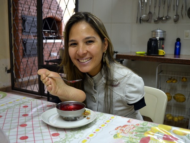 Sem o auxílio de ninguém Carolina utiliza os pés para comer (Foto: Fernanda Zanetti/G1)