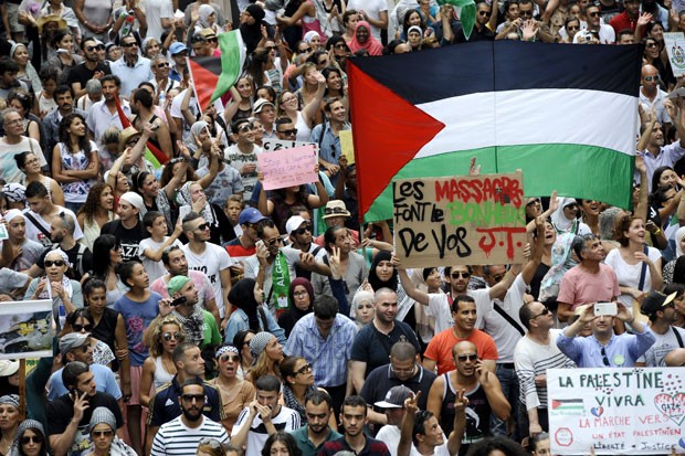 Em Marseille, franceses que protestam a favor dos palestinos carregam cartaz com os dizeres 'Massacre são o deleite do seu noticiário' e 'Palestina viverá'. (Foto: Franck Pennat/France Presse)