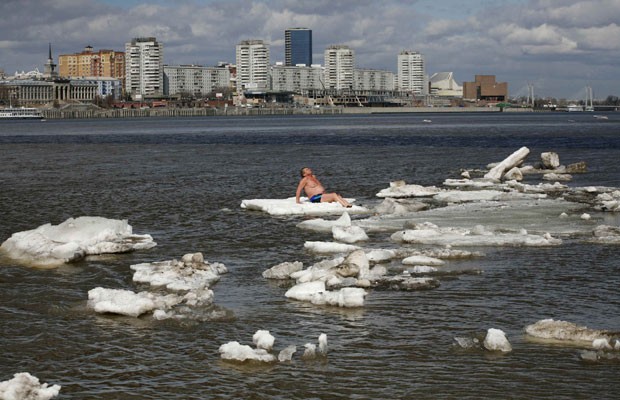 Russo toma banho de sol sobre um bloco de gelo no rio Yenisei, em Krasnoyarsk (Foto: Ilya Naymushin/Reuters)