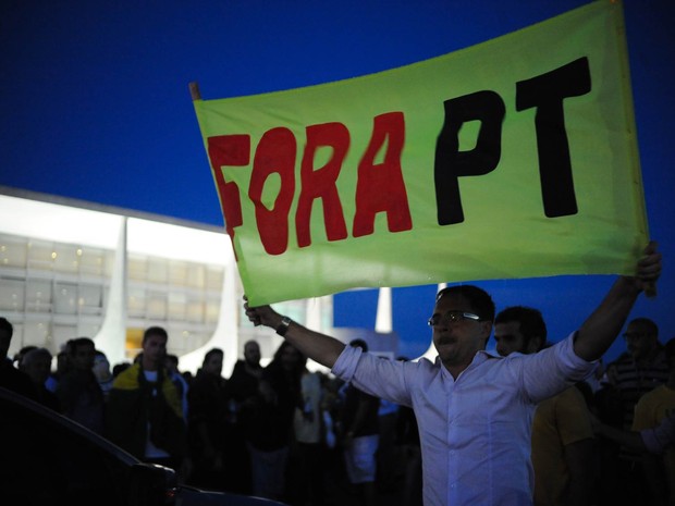 Manifestante ergue faixa em protesto contra a nomeação do ex-presidente Lula como ministro da Casa Civil, em frente ao Palácio do Planalto (Foto: Andressa Anholete/AFP)