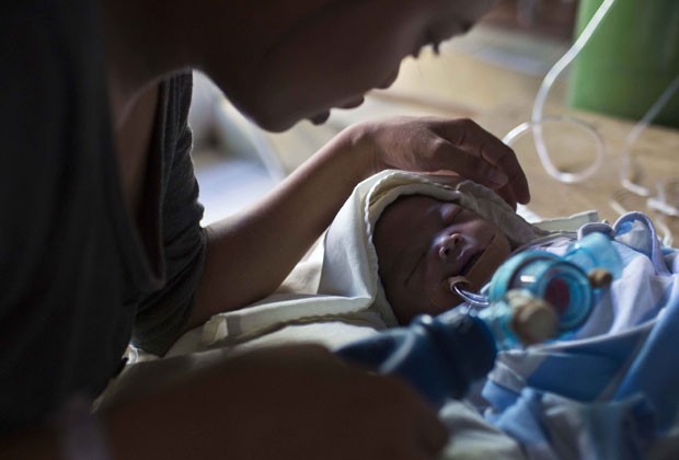 Genia Mae Mustacisa bombeia ar para os pulmões de sua filha de 3 dias em hospital de Tacloban, nas Filipinas, neste sábado (16); menina morreu no mesmo dia (Foto: David Guttenfelder/AP)