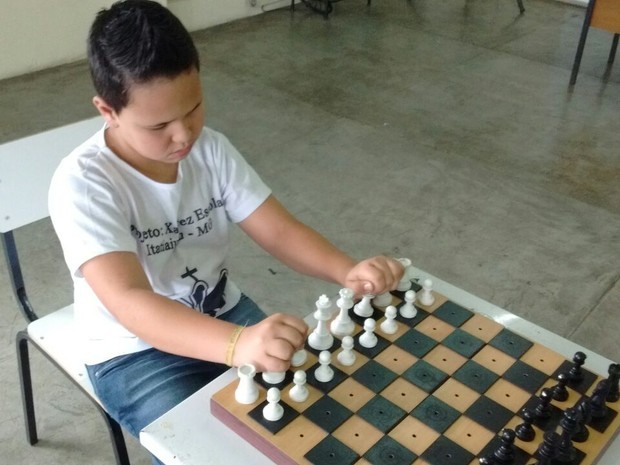 Menino com deficiência jogando xadrez com um amigo jogador com