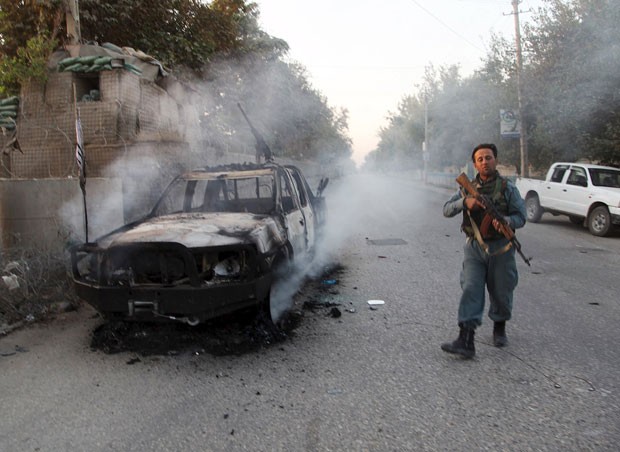 Policial afegão patrulha rua perto de veículo em chamas em Kunduz nesta quinta-feira (1º) (Foto: Reuters)