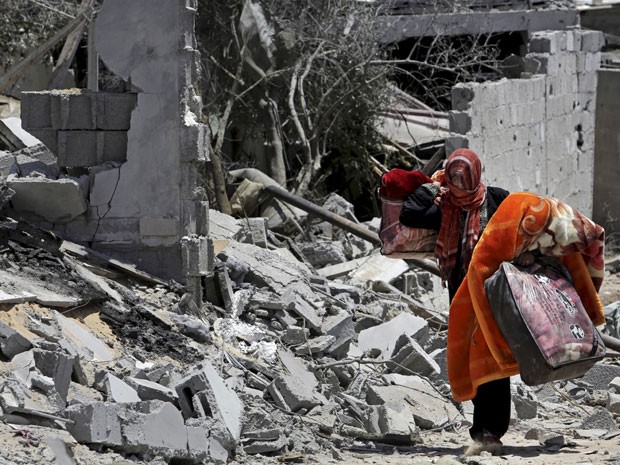 Mulher retira pertences de orpedui destrupido em Beit Lahiya, no norte da Faixa de Gaza (Foto: Adel Hana/AP)