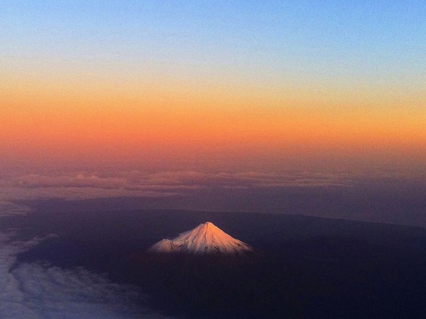 O cume do Monte Taranaki, na Nova ZelÃ¢ndia, Ã© visto no domingo (12), prÃ³ximo Ã  nuvem de cinzas expelida ao longo da semana anterior pelo vulcÃ£o chileno Puyehue. As cinzas causaram cancelamentos de voos na AustrÃ¡lia e na Nova ZelÃ¢ndia. (Foto: AP)