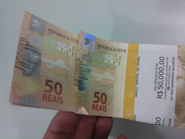 Cédula falsa e verdadeira ao fundo, com fita do Banco Central (Foto: Divulgação / Polícia Federal)