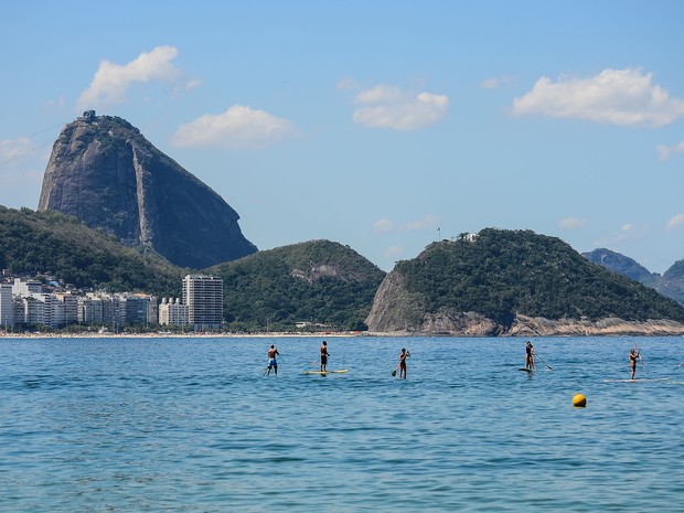 No Posto 6, em Copacabana, banhistas praticam stand up paddle com vista para o Pão de Açúcar (Foto: Marcelo Fonseca / Estadão Conteúdo)