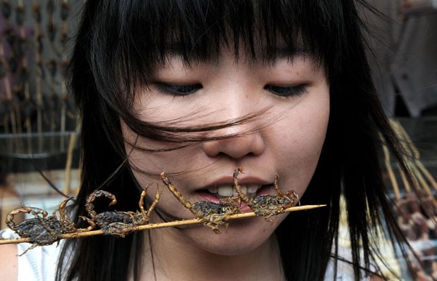 Chinesa come espetinho de escorpião em rua de Pequim, na China, em julho de 2008 (Foto: Mark Ralston/AFP)