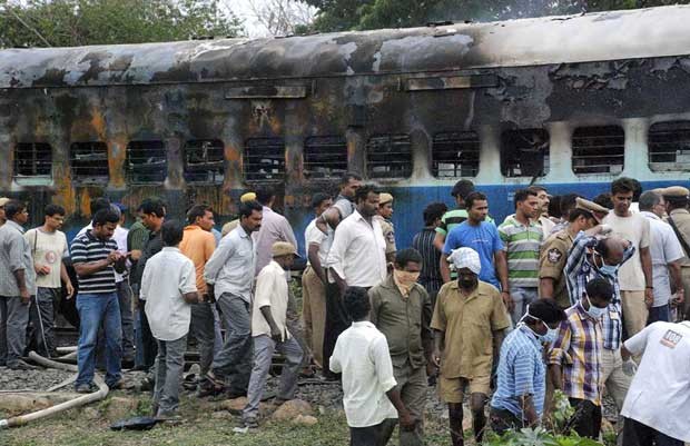 Indianos olham vagão de trem que pegou fogo (Foto: AP)