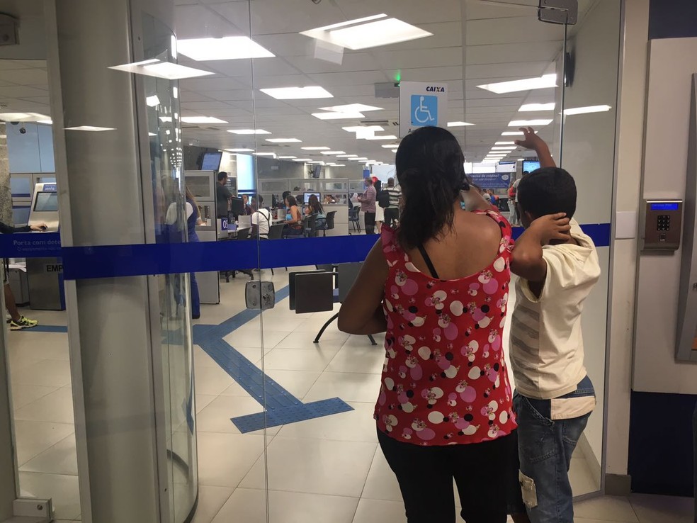 Mulher e filho aguardam por Jauvecir Delfino, que foi retirar FGTS no DF (Foto: Luiza Garonce/G1)