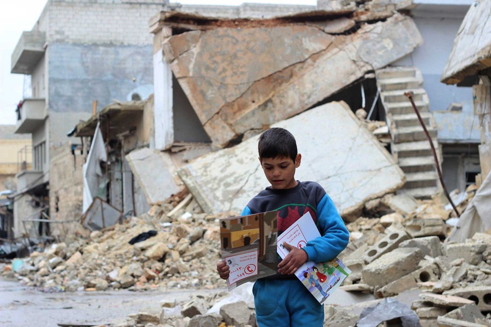 Foto de janeiro de 2017 que mostra criança carregando material distribuído pela Unicef em Al- Sakhoor, no Leste de Aleppo  (Foto: Khudr Al-Issa/ UNICEF via AP )