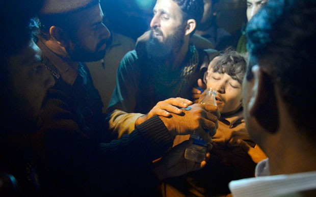 Equipes de resgate dão água para sobrevivente de desabamento de prédio em Lahore, Paquistão, nesta quarta-feira (4) (Foto: Arif Ali/AFP)