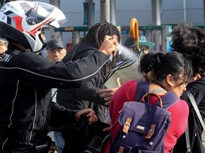 Policial joga spray de pimenta em uma manifestante na rodovia Raposo Tavares, em São Paulo. Funcionários e estudantes da Universidade de São Paulo (USP) fizeram barricadas no local em protesto contra a terceirização e o ajuste fiscal (Foto: Werther Santana/Estadão Conteúdo)