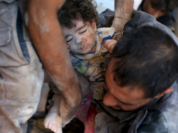 Menina é resgatada após bombardeio em área residencial na Síria (Foto: Bassam Khabieh / Reuters)