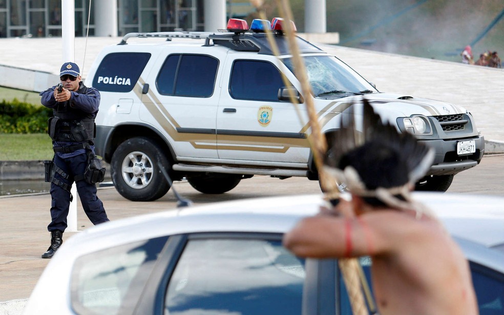 Policial e índio apontam armas, um contra o outro, durante protesto por demarcação de terras indígenas, em Brasília (Foto: REUTERS/Gregg Newton)