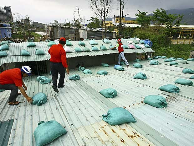 Voluntários da Cruz Vermelha e funcionários colocam sacos de areia sobre casas em Hoa Hai ala, no distrito de Ngu Hanh Son. (Foto: Tuan Tran Quang / VNRC / Via Reuters)