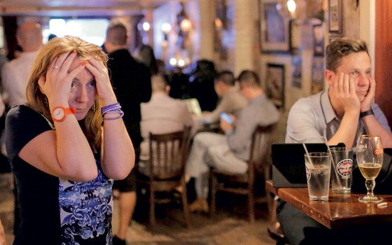 Britânicos reunidos num pub reagem com perplexidade ao resultado do referendo (Foto: Andrew Kelly / Reuters)