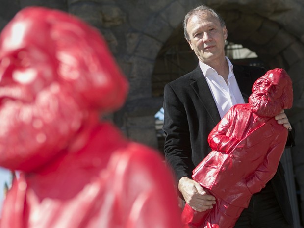 O artista alemão Ottmar Hoerl segura um boneco de Karl Marx; 500 esculturas com a figura do comunista estão em exposição na cidade de Tréveris, na Alemanha, até o dia 26 de maio (Foto: Thomas Wieck/AFP)