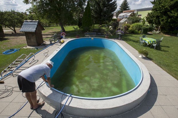 Harald Dobrauer começou a limpar sua piscina que ficou isolada em meio à inundação do rio Elba (Foto: Thomas Peter/Reuters)