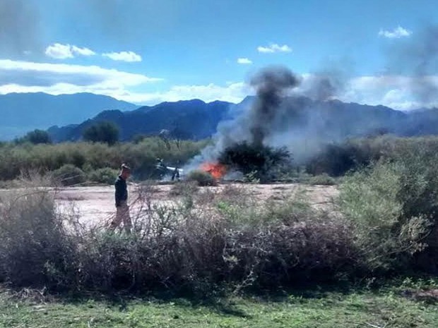 Homem passa em frente às chamas do que restou de um helicóptero envolvido no acidente aéreo envolvendo outro helicóptero durante gravação do reality show europeu 'Dropped' perto de Villa Castelli, na Argentina. As 10 pessoas a bordo morreram no acidente (Foto: Gabriel Gonzalez/AP)