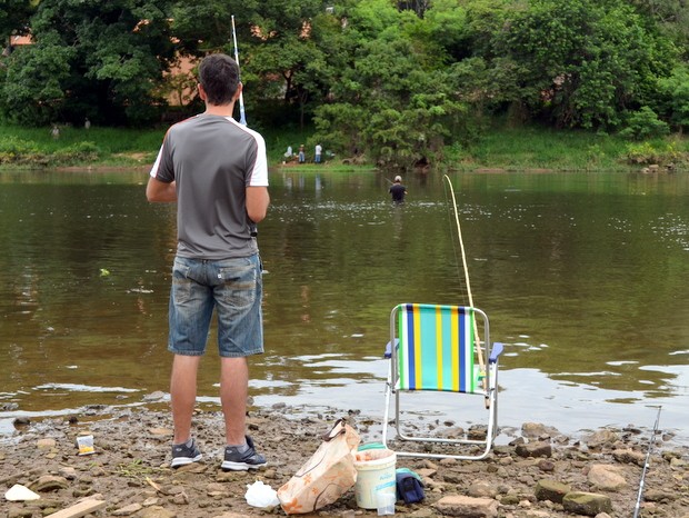 Rapaz pescou na beira do rio e outro se arriscou ao pescar dentro do manacial em Piracicaba (Foto: Camila Ancona/G1)