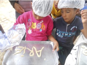 Crianças escrevendo na assadeira (Foto: Divulgação/ Ser Criança)