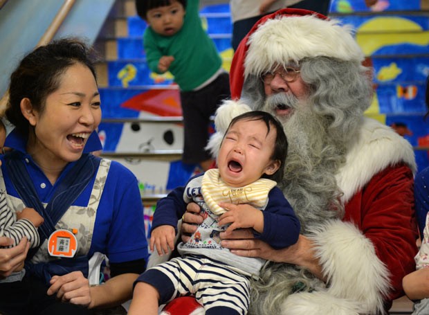 Crianças posam com Papai Noel nesta segunda-feira (9) em Tóquio (Foto: Yoshikazu Tsuno/AFP)