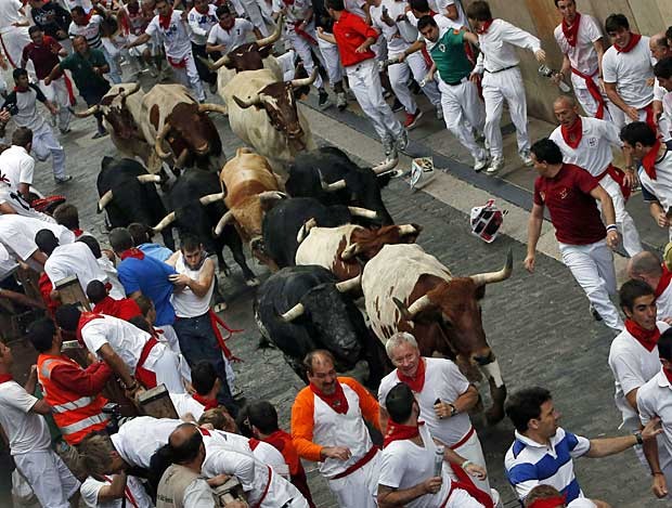 O festival de São Firmino em Pamplona, na Espanha, realizou neste sábado (7) a sua primeira corrida de Touros, a principal atividade da festa. Os animais foram soltos para perseguir centenas de pessoas ao longo de 850 metros até a praça central da cidade. (Foto: Susana Vera / Reuters)