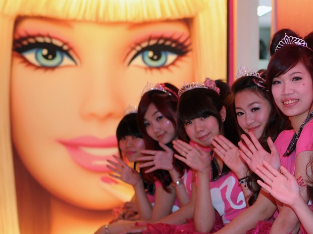 Garçonetes na frente de um cartaz Barbie durante a cerimônia de abertura de um restaurante temático  (Foto: AFP PHOTO / Sam Yeh)